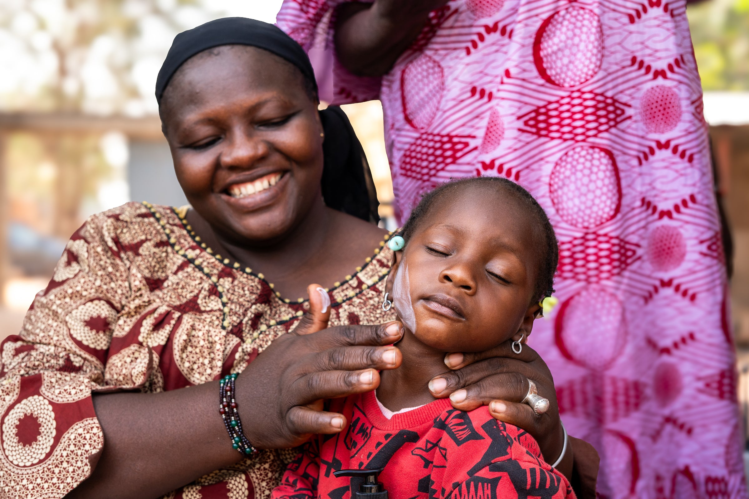 Woman in Mali applying shea butter to a child's face