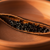 Split vanilla bean in a shallow terracotta bowl