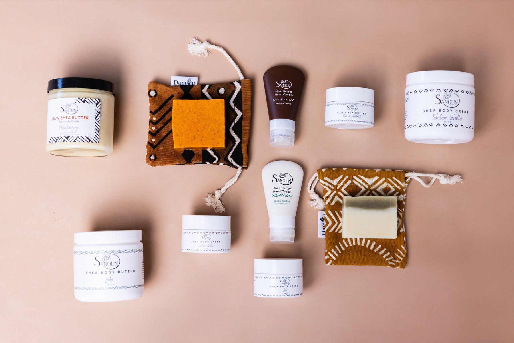 Sanoun raw shea butter, body care, hand creams, and soaps arranged on a warm neutral background